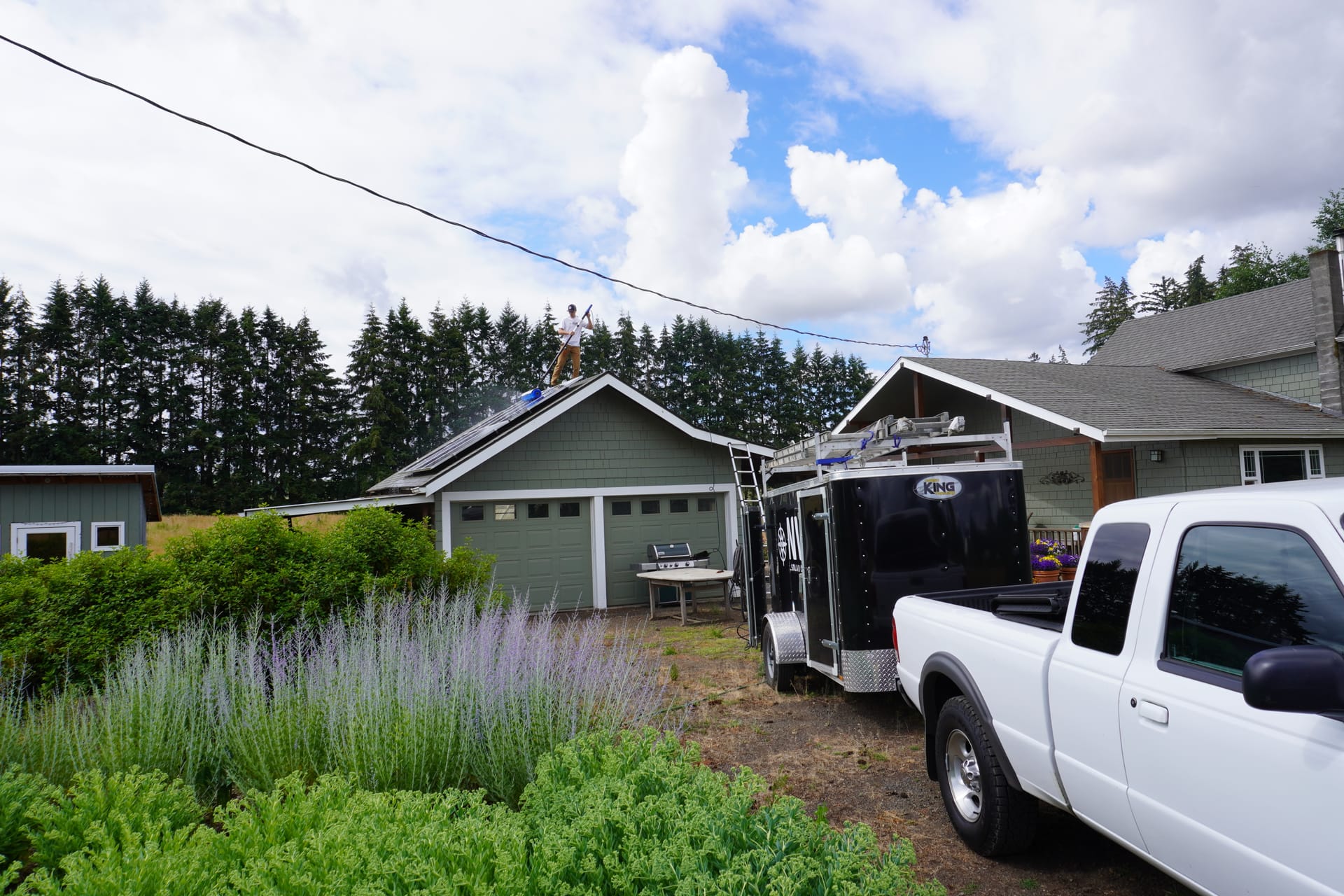 Technician cleaning rooftop solar panels with a water-fed pole, serving Oregon City, OR