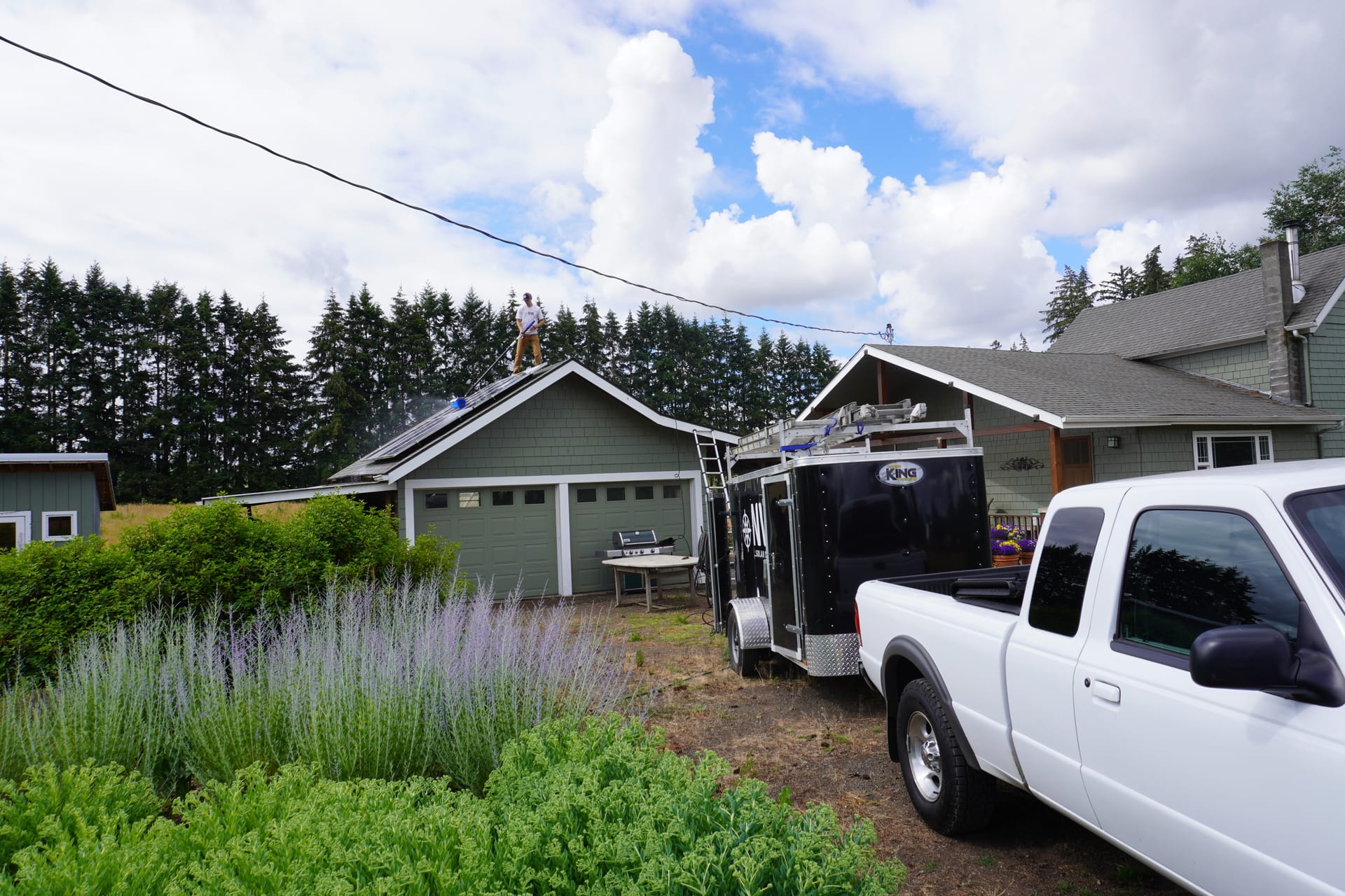 The NW Solar Clean truck and equipment trailer at a residential job, technician on the roof