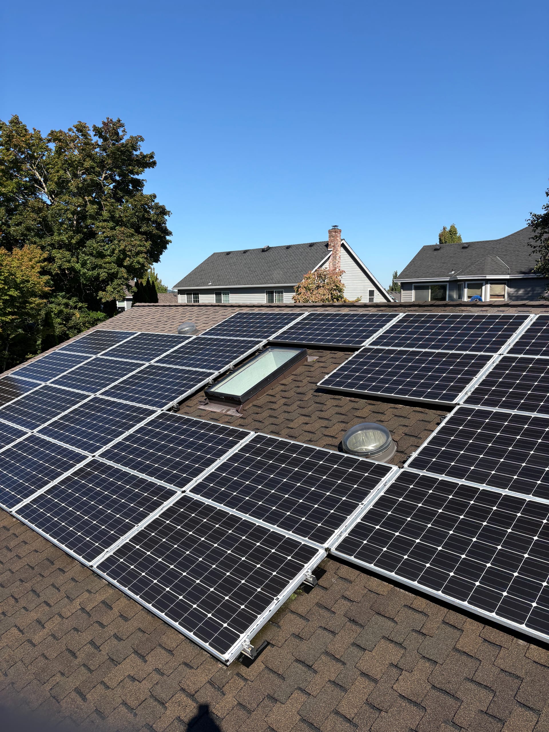 A clean residential rooftop solar array on a shingle roof under a blue sky